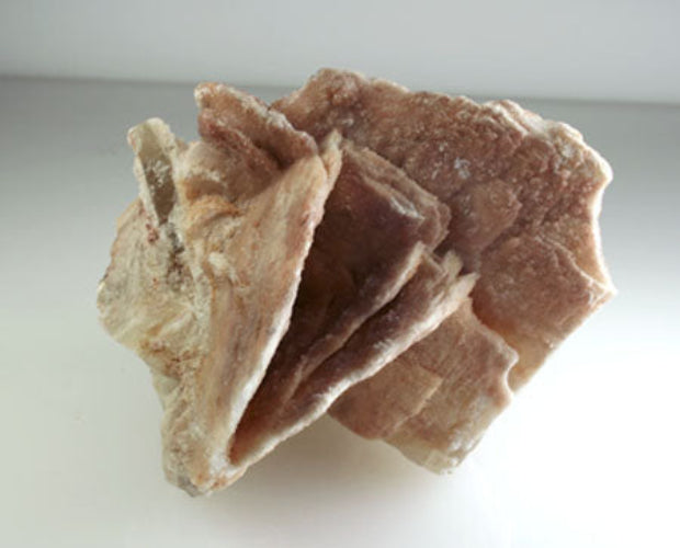 A photograph of two large pinkish brown barite blades with some smaller intergrown crystals, showing clear barite crystallization in the sides.